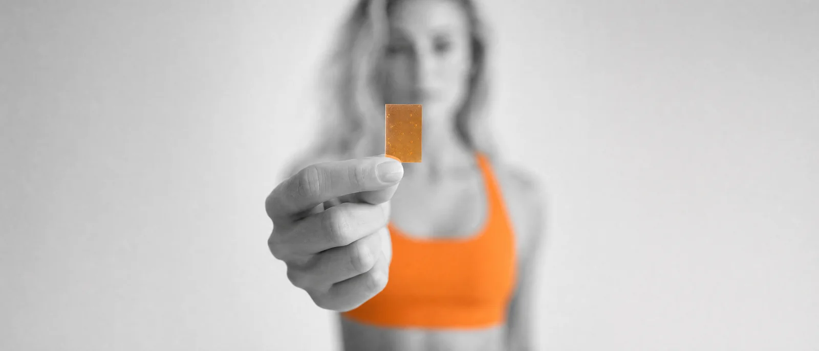 A woman holding a single orange strip out to the camera.