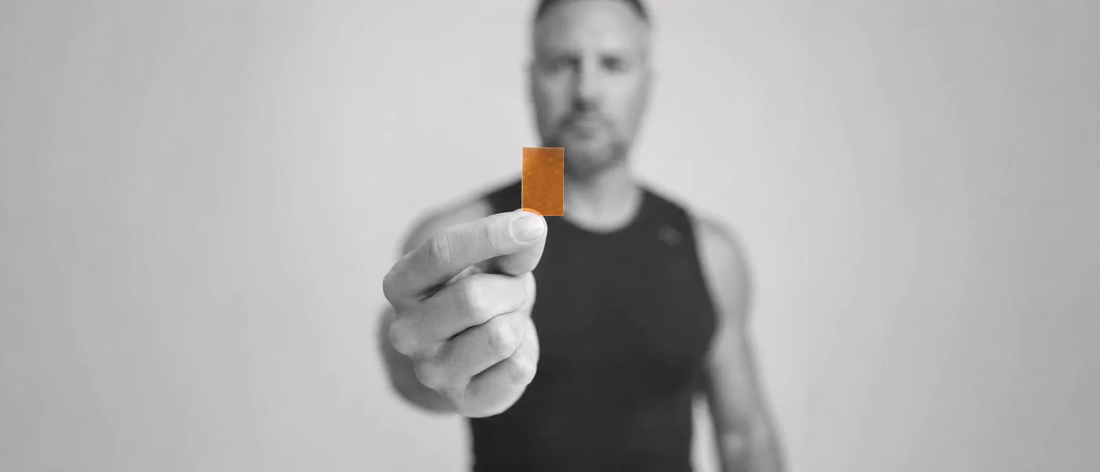 A man holding a single orange strip out to the camera.